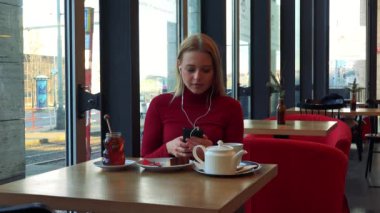 kadın bir kafe ve bir smartphone cep telefonu ile müzik dinler 
