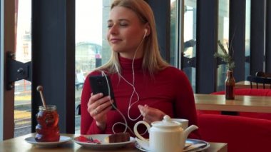 kadın bir kafede bir smartphone cep telefonu ile müzik dinler 