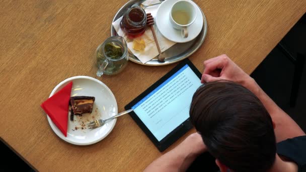 Een man in een cafe leest een tekst op zijn Tablet PC — Stockvideo