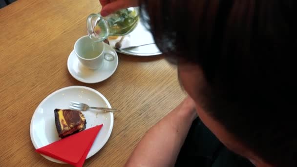 Een man in een cafe geniet ijs thee en taart — Stockvideo