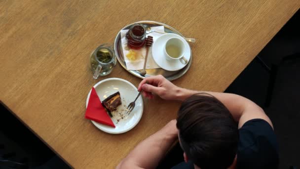 Ein Mann in einem Café und genießt Kuchen mit Tee — Stockvideo