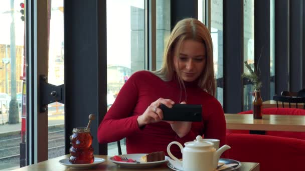 Vrouw in een café en neemt een foto van haar maaltijd — Stockvideo