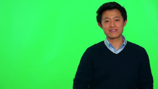 Азиатский мужчина машет рукой и улыбается в камеру — стоковое видео