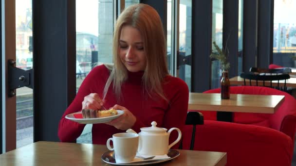 Vrouw zit in een café met ontbijt op tafel — Stockvideo
