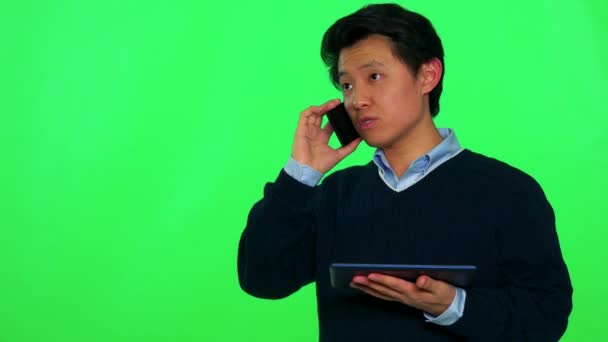 Азіатських людині переговори на смартфоні під час проведення планшета — стокове відео