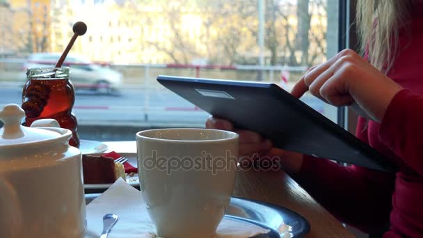 Uma mulher em um café e trabalha em um tablet — Vídeo de Stock