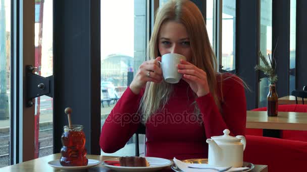 Woman in a cafe drinks tea and smiles — Stock Video