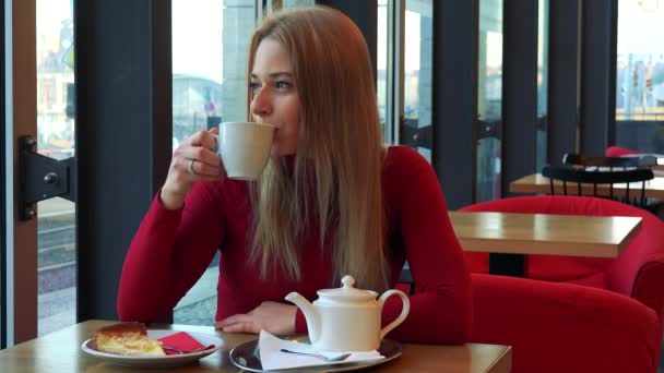Donna si siede in un caffè con la colazione sul tavolo — Video Stock