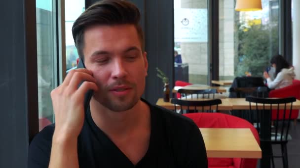 Mann im Café und spricht auf Smartphone — Stockvideo