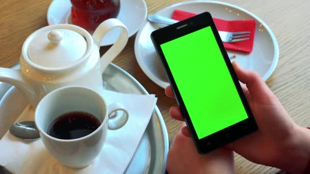 Een vrouw houdt een smartphone met een groen scherm — Stockvideo