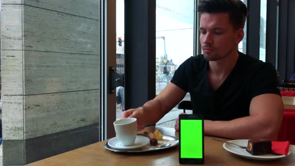 Homme mange tarte et boissons thé avec un smartphone — Video