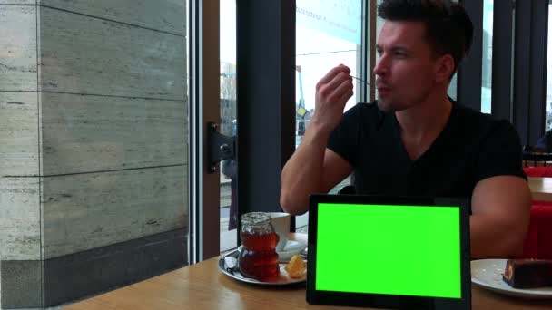 Muž jí koláč a pije čaj s tabletem — Stock video