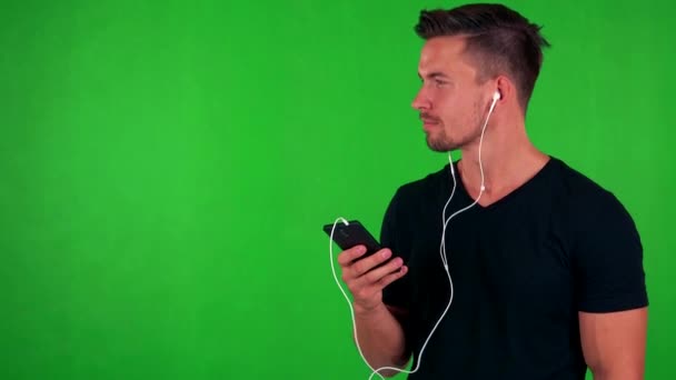 Чоловік слухає музику з навушниками на смартфоні — стокове відео