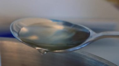 Bir kadın petrol tablespoonfuls ölçer ve onları dökülen 