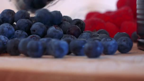 Blueberries are poured onto a wooden board on a kitchen unit — Stock Video