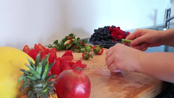 Een vrouw bereidt aardbeien op een aanrecht — Stockvideo