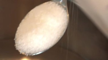 Bir kadın şeker teaspoonfuls ölçer ve onları dökülen 