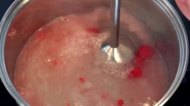 Bir kadın bir suda bir karıştırıcı ile Ahududu liquidizes 
