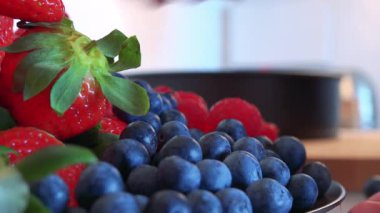 Bir kadın bir kase çilek yığını yaban mersini koyar 