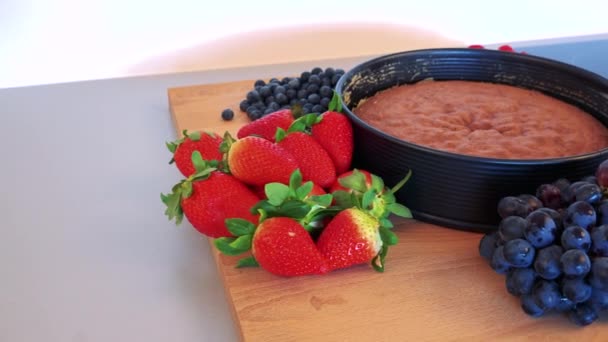 En kaka som bas i en form och olika sorters frukt — Stockvideo