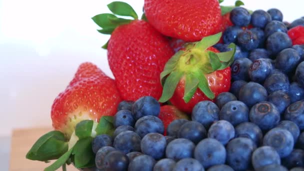 Blaubeeren, Erdbeeren und Himbeeren in einer Schüssel auf dem Küchentisch — Stockvideo