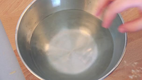 Uma mulher coloca lençóis de gelatina em uma tigela com água — Vídeo de Stock