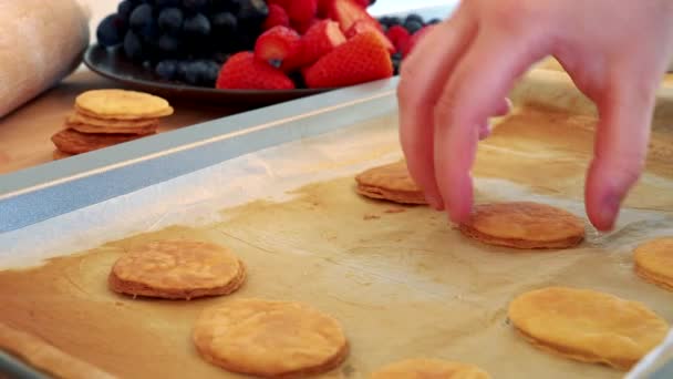 Een vrouw zet filodeeg gebak rondes van een bakplaat — Stockvideo