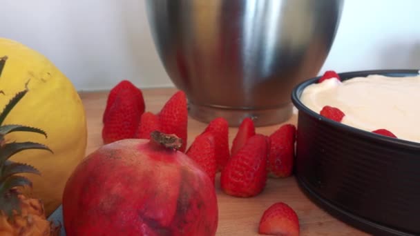 Bir formdaki bir pasta çevresinde mutfak tezgahı üzerinde meyve — Stok video