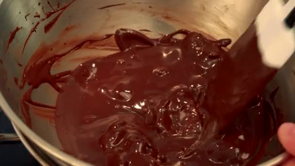 Halb geschmolzene dunkle Schokolade wird in einer Schüssel gerührt — Stockvideo