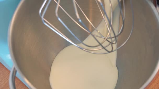 Milch wird mit dem Schneebesen eines elektrischen Rührwerks in eine Schüssel gegossen. — Stockvideo