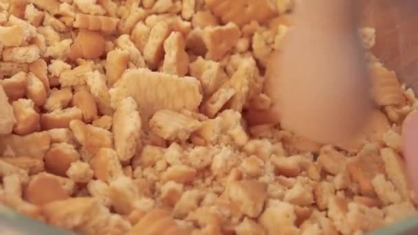 Les biscuits sont écrasés en miettes dans un bol avec un pilon 