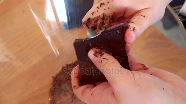 Een vrouw roosters een bar van donkere chocolade — Stockvideo