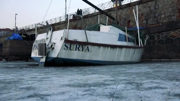 Лодка пришвартовалась у пристани на замерзшей реке — стоковое видео