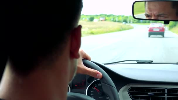 Άνδρας οδηγεί ένα αυτοκίνητο στο δρόμο — Αρχείο Βίντεο