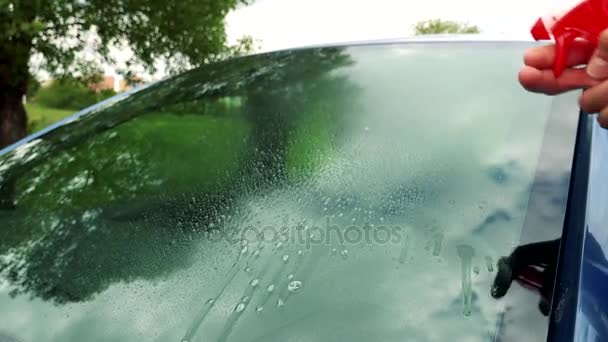 Человек чистит и полирует окно автомобиля — стоковое видео