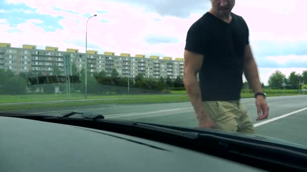 Человек открывает капот автомобиля и смотрит на двигатель — стоковое видео