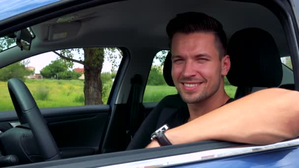 Man smiles to camera behind the wheel in the car — Stock Video