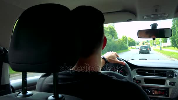 Мужчина водит машину по дороге в городе — стоковое видео
