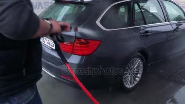 Bir adam bir hortum ile arabasının arka yıkar