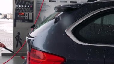 Bir adam bir hortum ile arabasının arka yıkar 