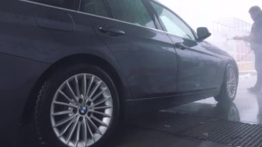 Bir adam bir hortum ile arabasının ön yıkar 