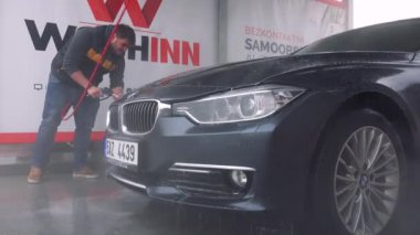 Bir adam bir hortum ile arabasının ön yıkar