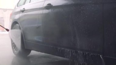 Bir adam bir hortum arabasını yıkar