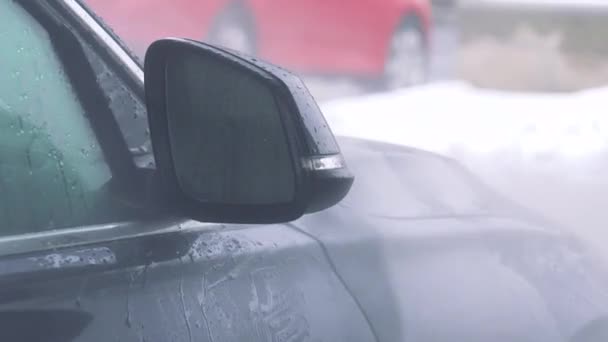 Ein Mann wäscht die Seite seines Autos mit einem Schlauch — Stockvideo