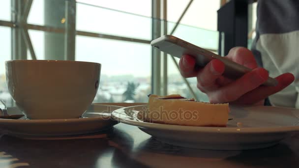 A man with breakfast in a cafe and works on a smartphone — Stock Video