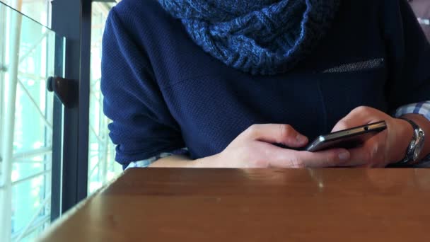 Um homem em um café e trabalha em um smartphone — Vídeo de Stock