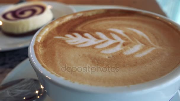 Primer plano en la parte superior de una taza de café con arte latte — Vídeos de Stock