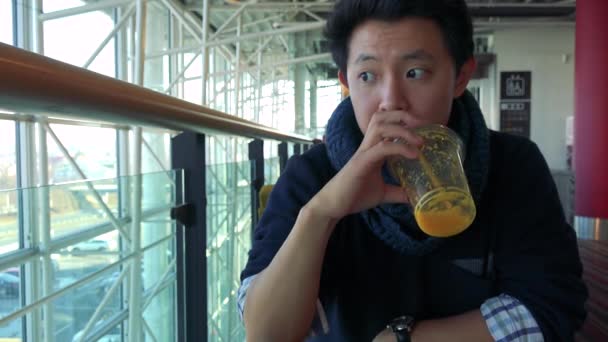 Hombre en un café en un centro comercial y termina una bebida fría — Vídeos de Stock