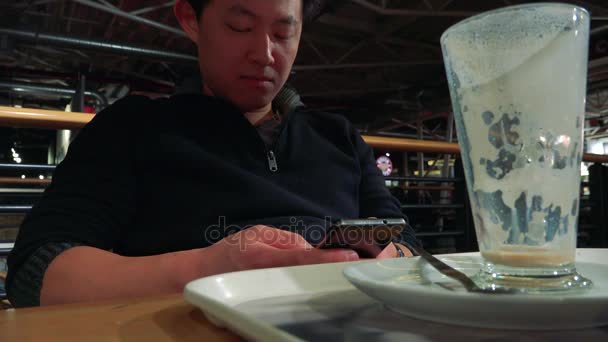 Hombre en un café y trabaja en un teléfono inteligente — Vídeo de stock