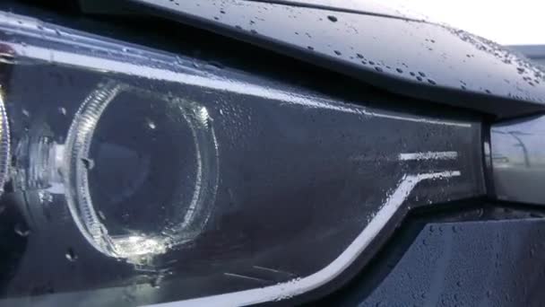 Closeup on a headlight of a wet car — Stock Video